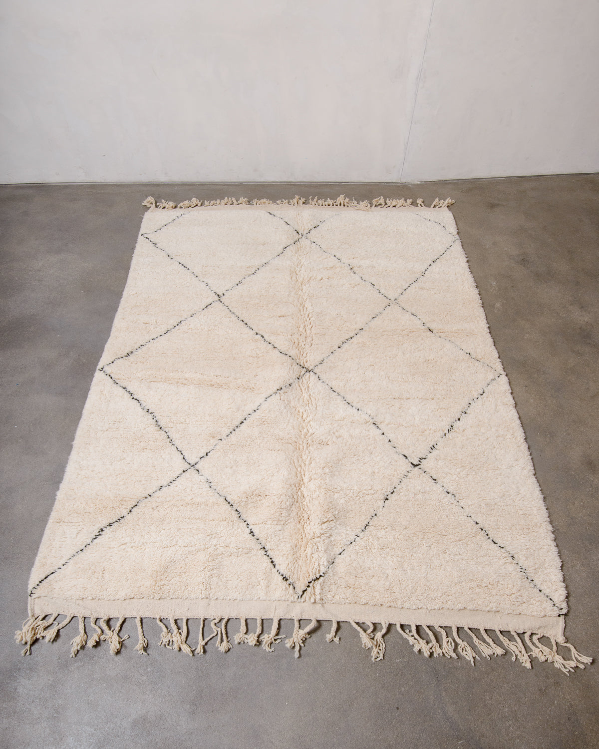 Berberlin Beniourain rug with black line design laying flat on concrete floor.